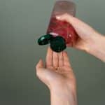 a person squeezing lubricant out of a bottle