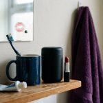 Black stroker canister beside red lipstick, with a lipstick kiss on the bathroom mirror